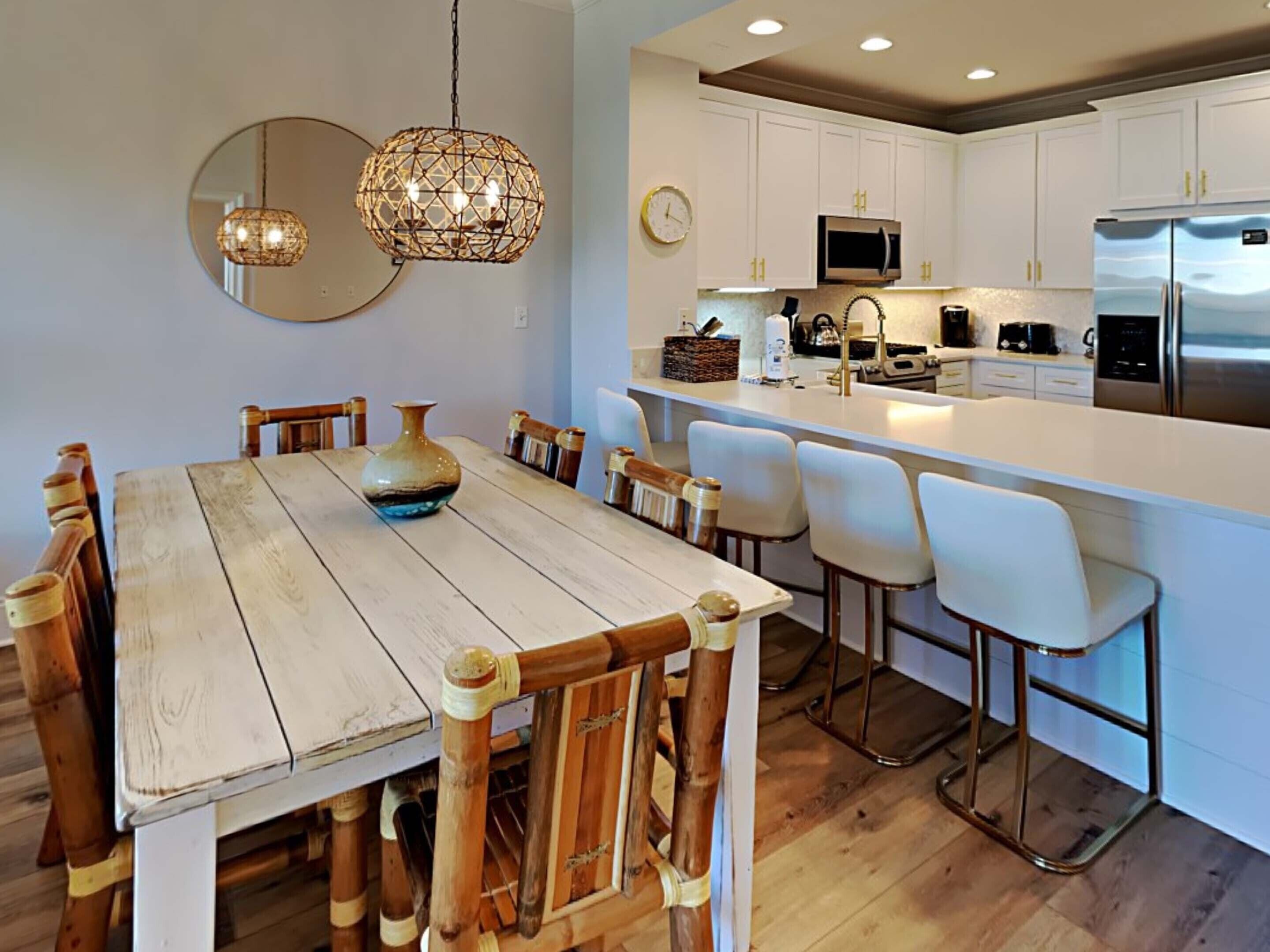 A modern kitchen with white cabinets, stainless steel appliances, and a wooden dining table with chairs.