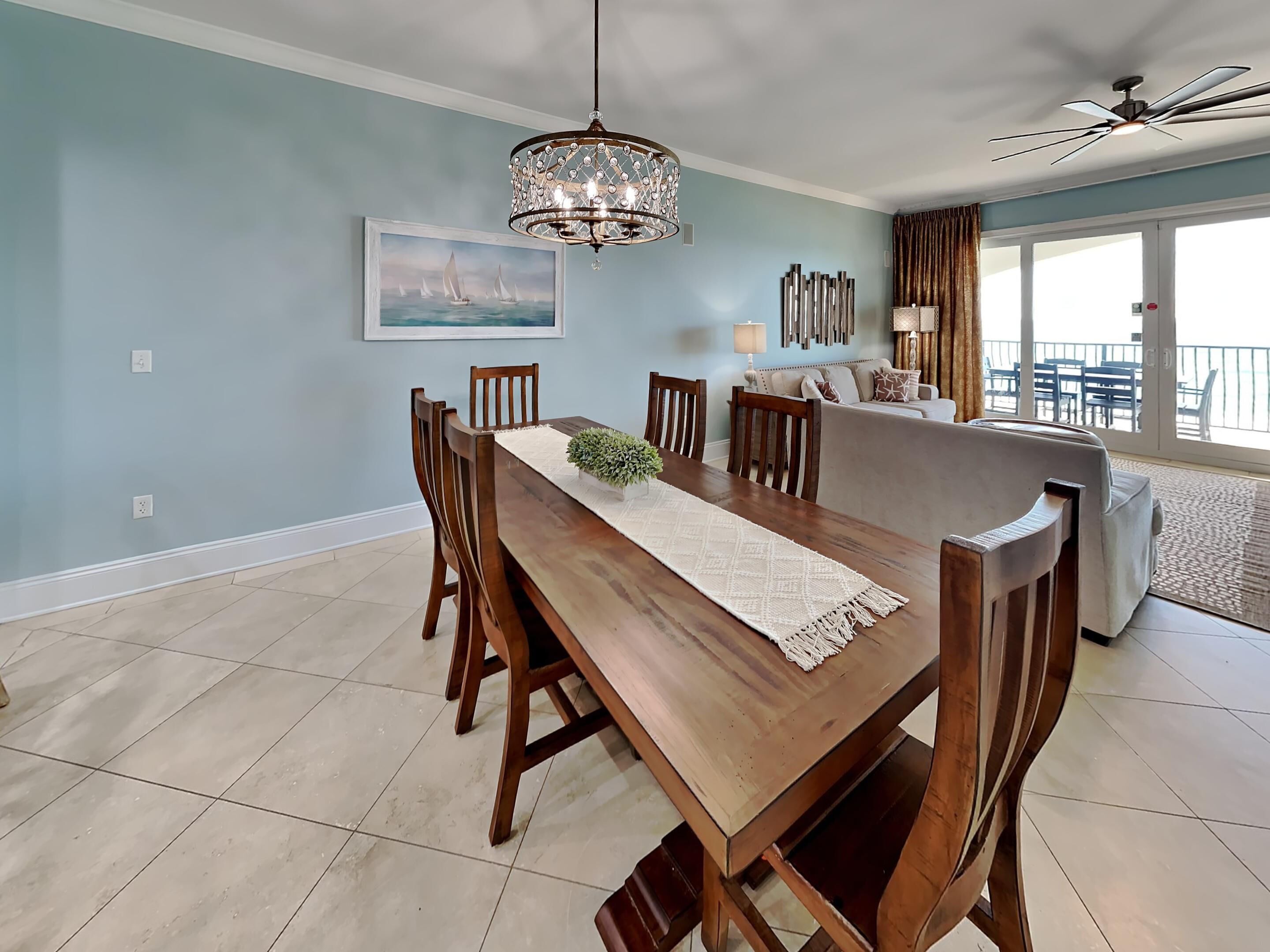 A dining area with a wooden table, chairs, a chandelier, and a painting on the wall.