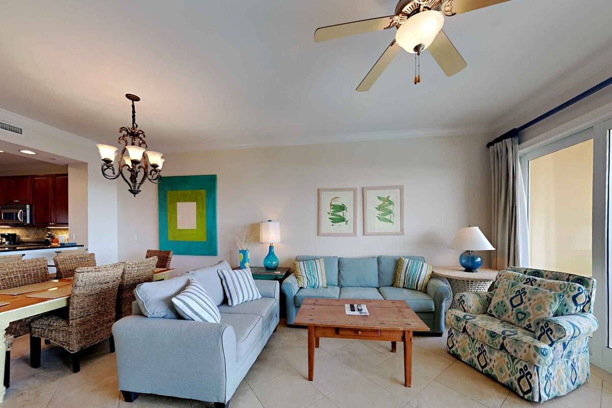 A spacious living room with a sofa set, a coffee table, and a ceiling fan.