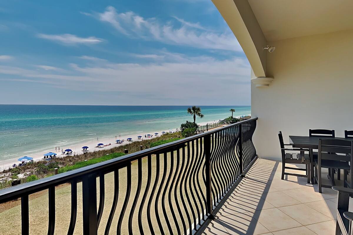 A balcony with a view of the beach and ocean.