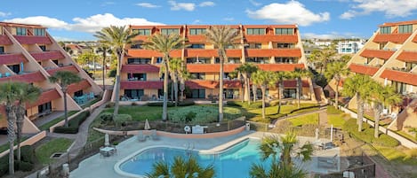 Ein Hotel mit Pool, Außenbereich und Palmen.