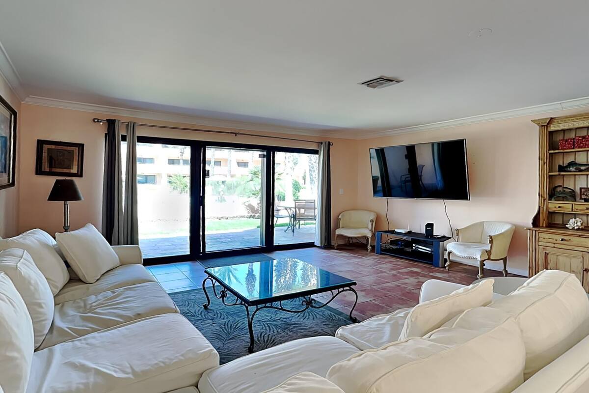 A living room with a sofa, a coffee table, a TV, and a sliding glass door leading to an outdoor area.