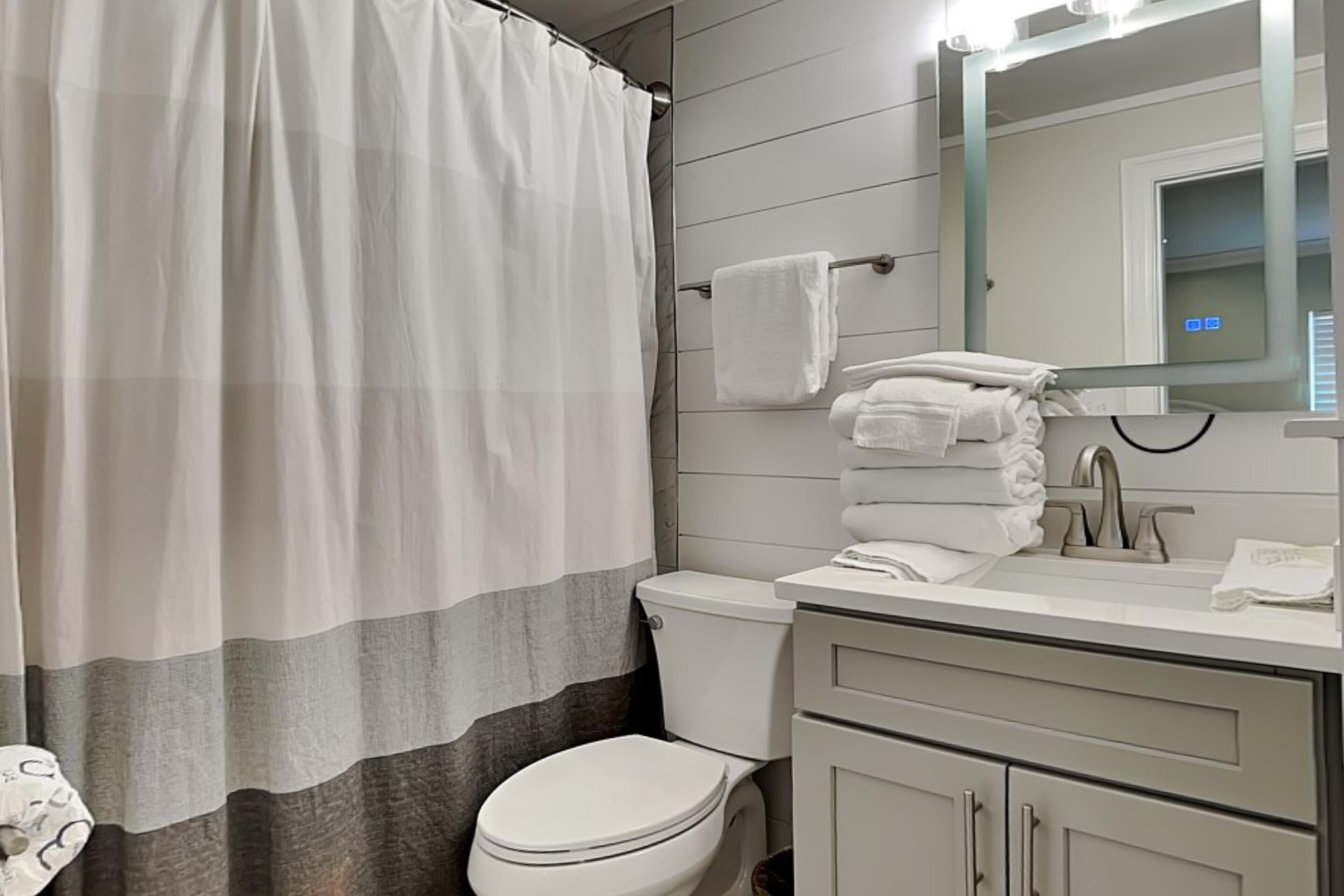 A modern bathroom with a toilet, sink, and mirror.