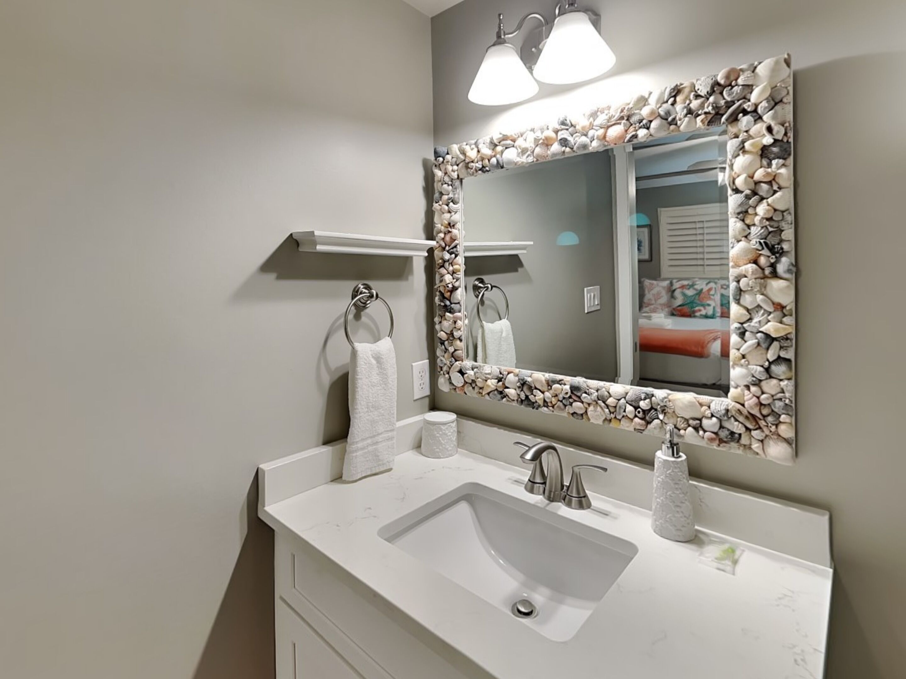 A bathroom with a white sink, a mirror with a stone frame, and a towel rack.