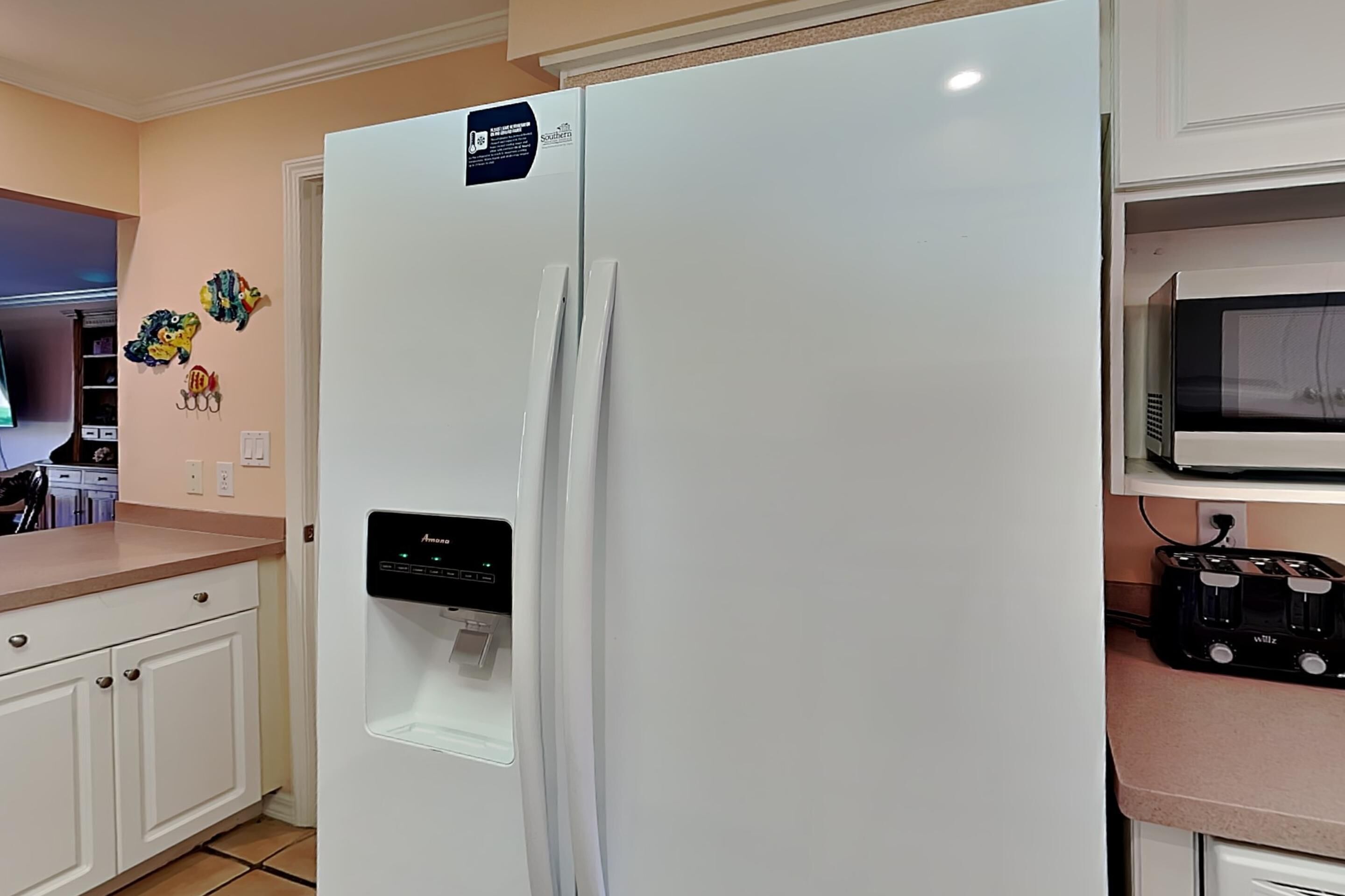 A kitchen with a white refrigerator, a microwave, and a water dispenser.