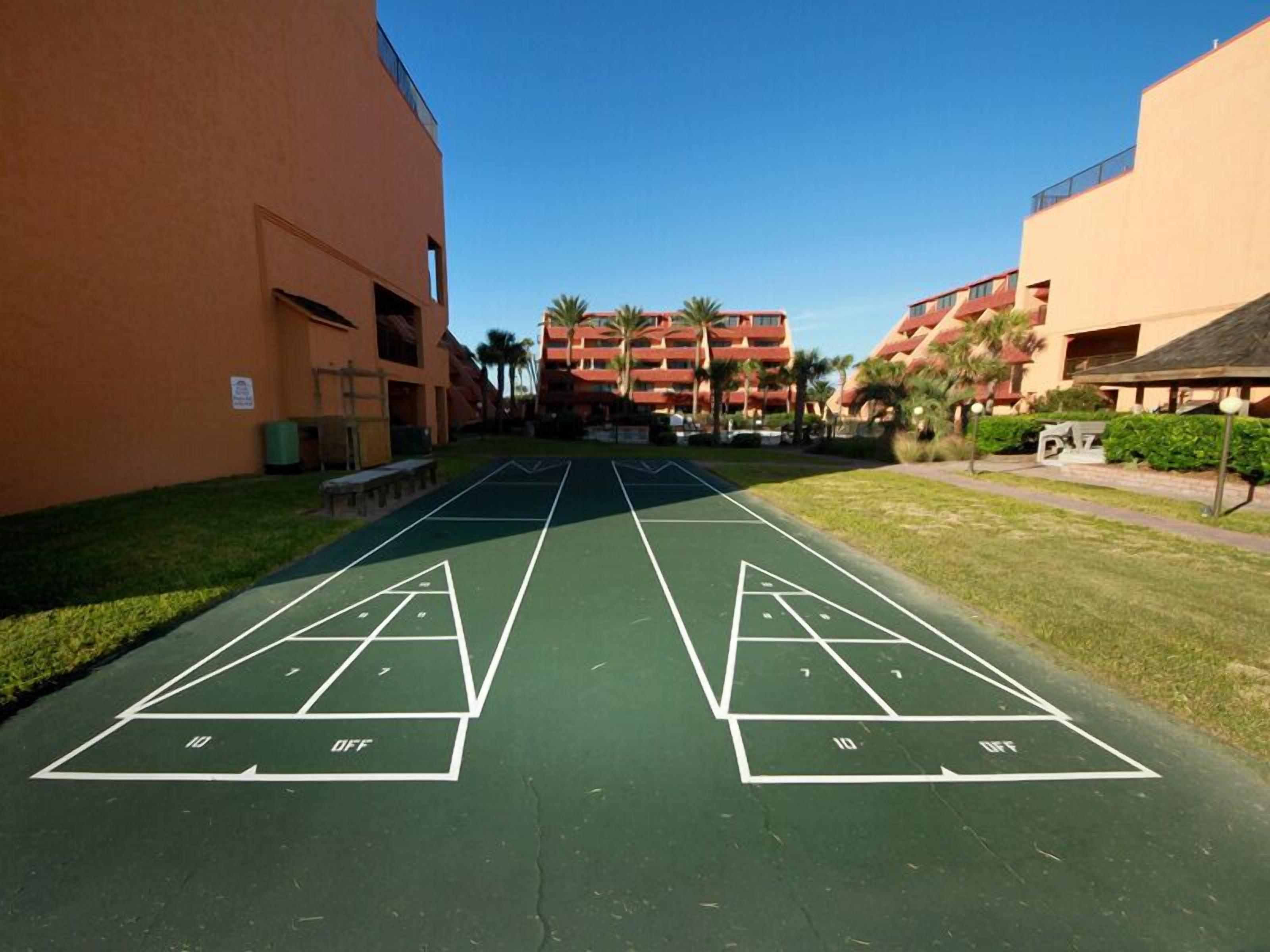 A shuffleboard court with a building in the background.