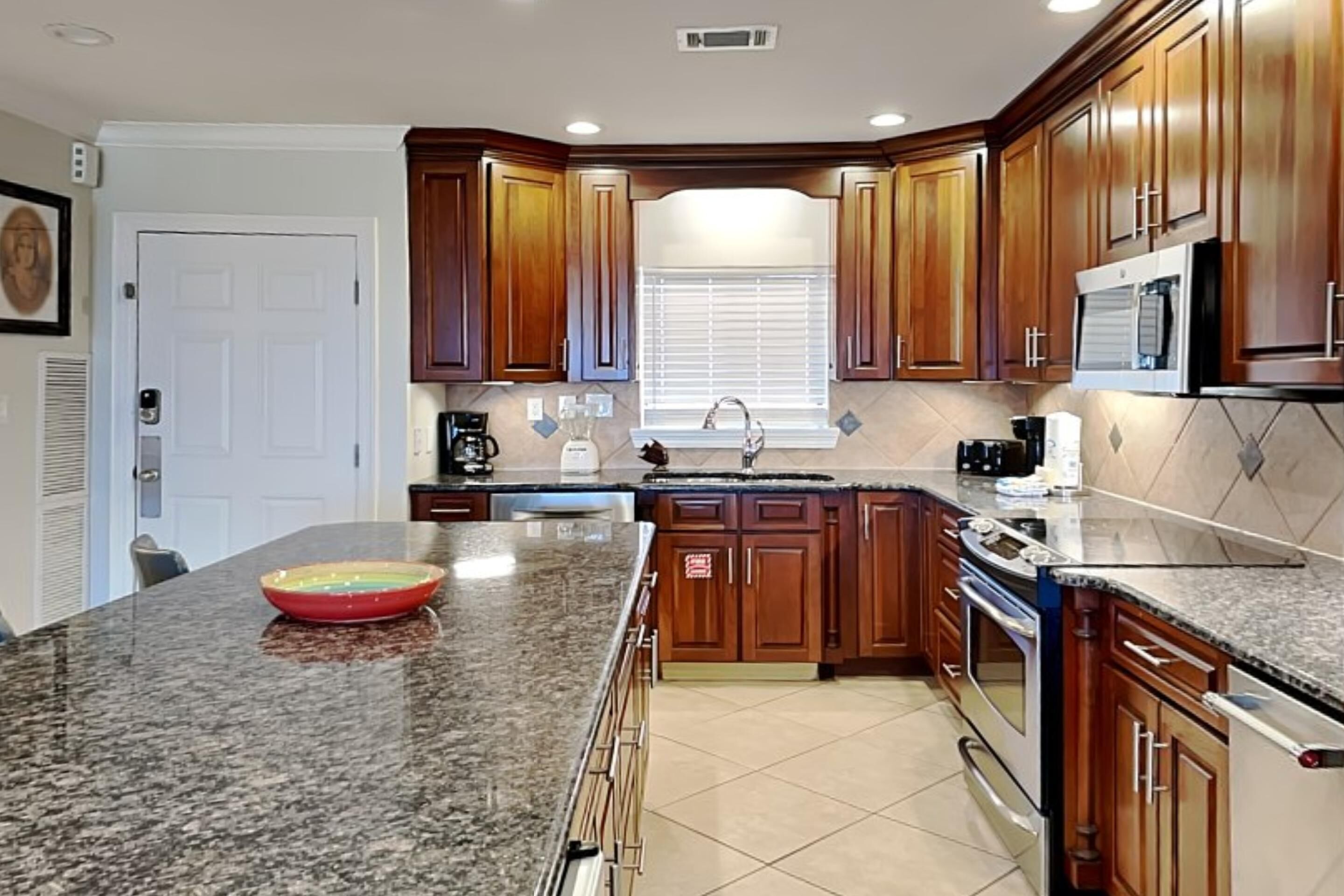 A kitchen with granite countertops, wooden cabinets, a built-in oven, and a microwave.