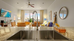 A modern kitchen with a stainless steel sink, a ceiling fan, and a large window with curtains. - Alerio by Southern Vacation Rentals (Miramar Beach)