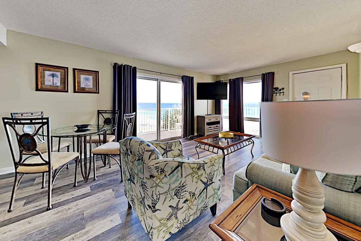 A living room with a balcony, a dining area, and a TV.