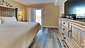 Une chambre d’hôtel avec un lit, une télévision, une commode et une fenêtre avec des rideaux.