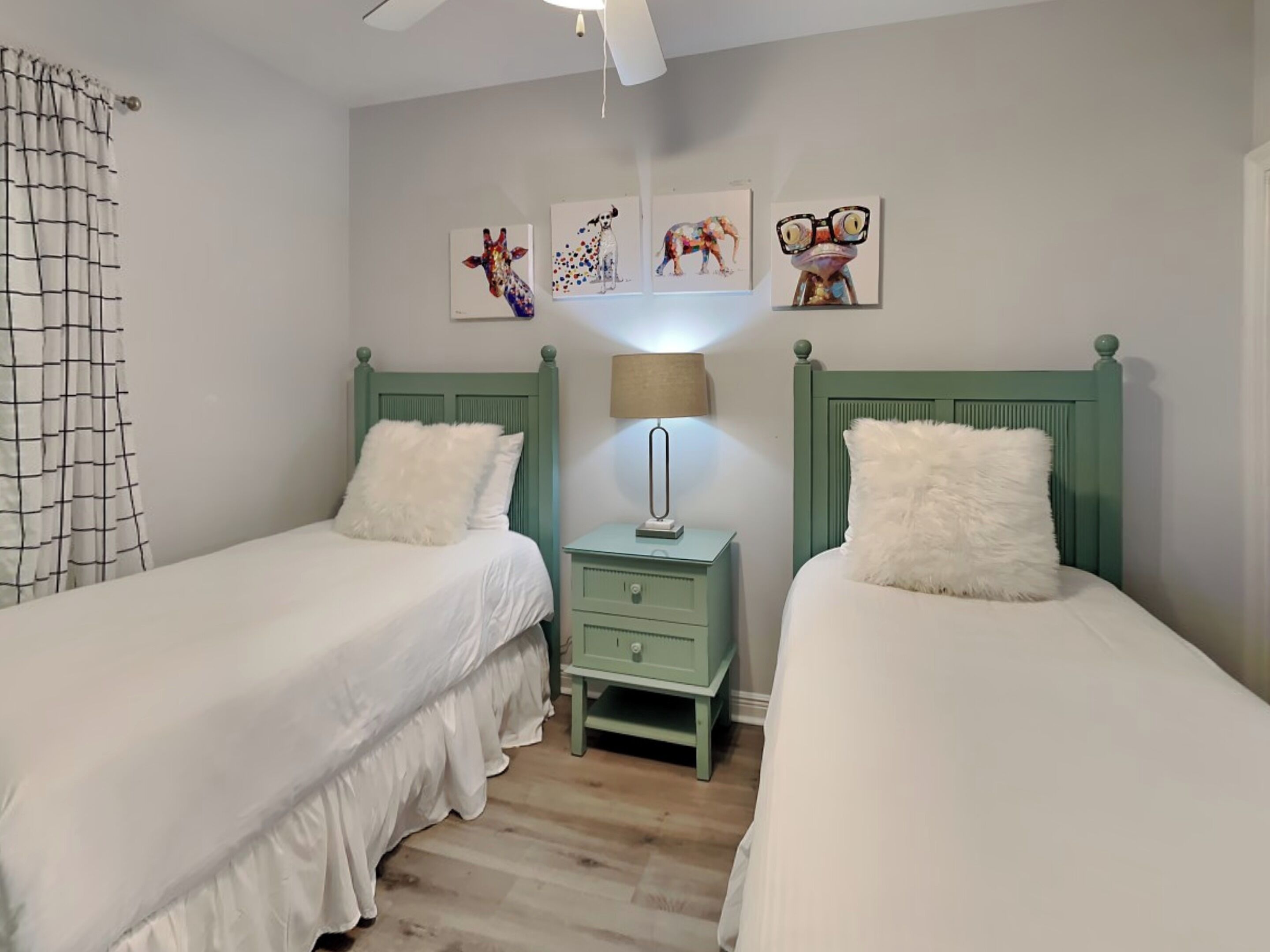 Een slaapkamer met twee bedden, een nachtkastje en decoratieve wandkunst.