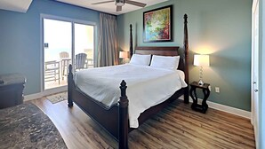 A bedroom with a large bed, a ceiling fan, a painting, and a view of the outside. - Ariel Dunes II by Southern Vacation Rentals (Miramar Beach)