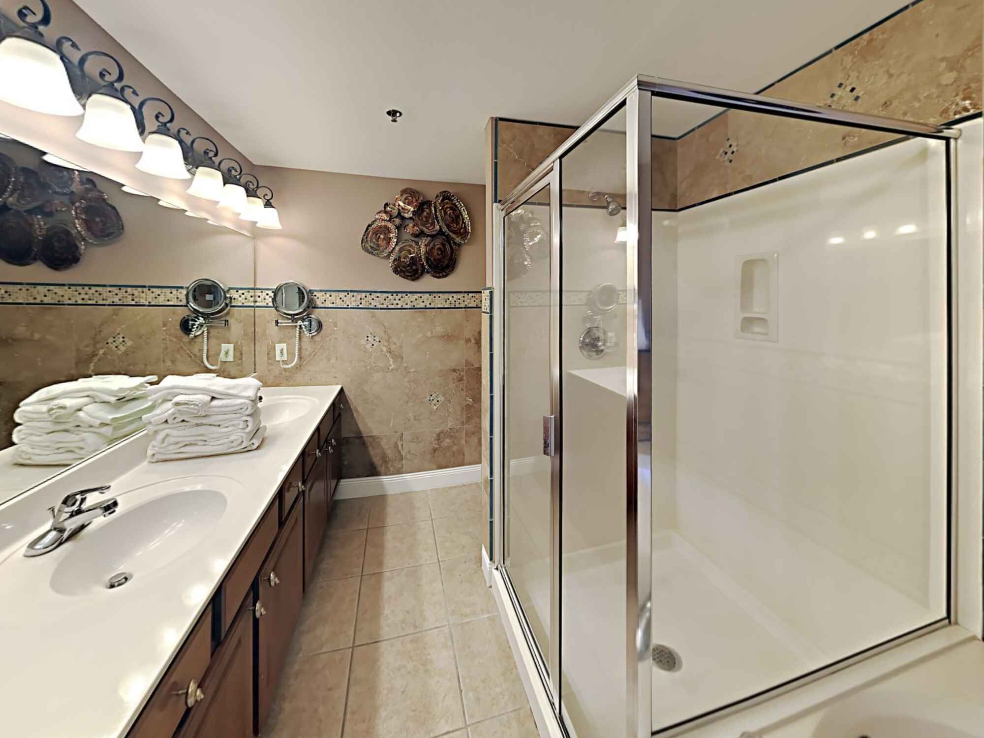 A modern bathroom with a glass-enclosed shower, a vanity with a sink and mirror, and decorative wall art.