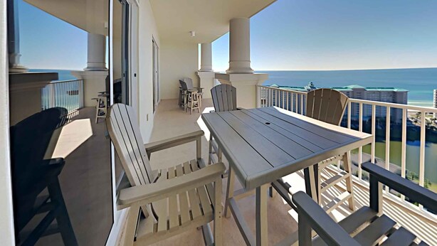 A balcony with a wooden table and chairs, overlooking the ocean. - Ariel Dunes II by Southern Vacation Rentals (Miramar Beach)