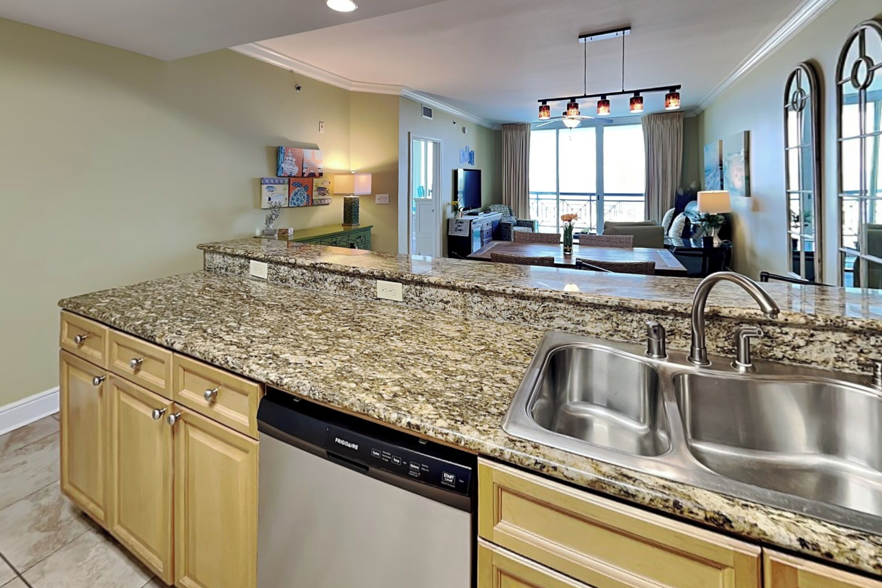 A kitchen with granite countertops, a dishwasher, and a stainless steel sink.