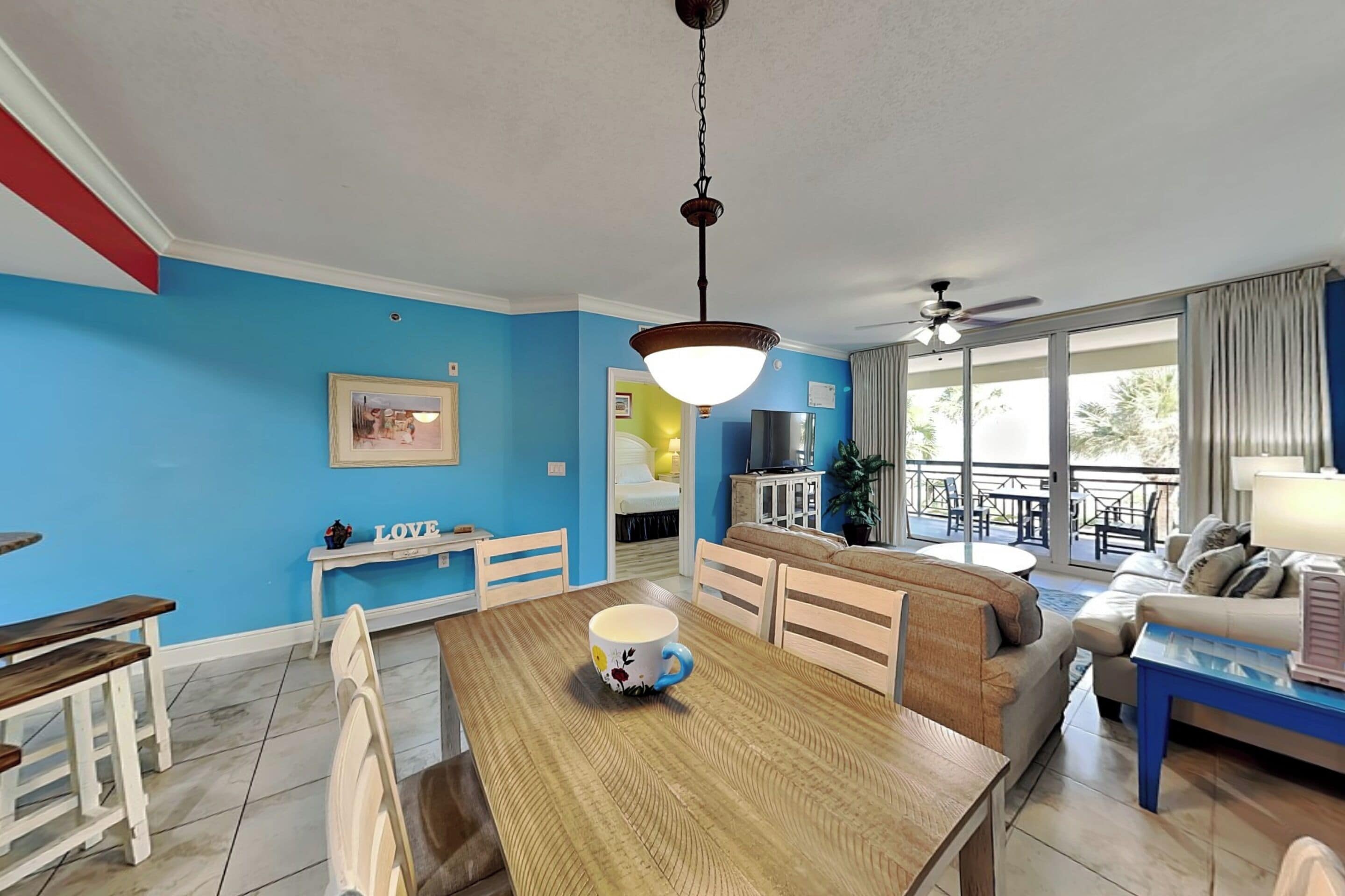 Una sala moderna con comedor, una cocina al fondo y un balcón con mobiliario exterior.