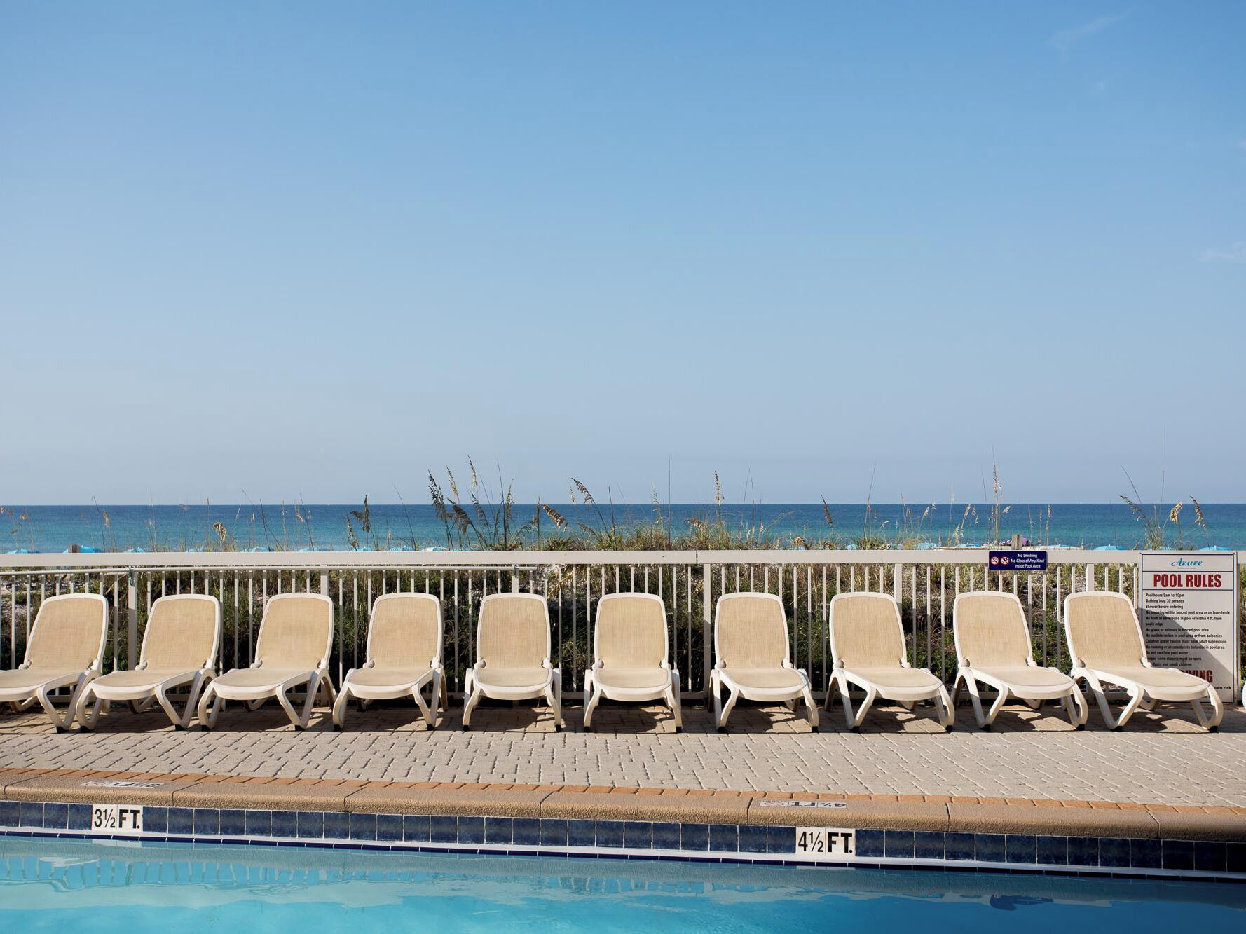 Un espace aménagé au bord de la piscine, avec des chaises longues et un panneau indiquant les règles à respecter.