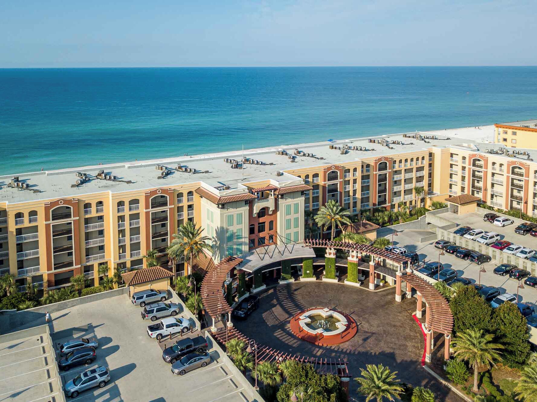 A hotel with a central courtyard, multiple parking levels, and a beach view.