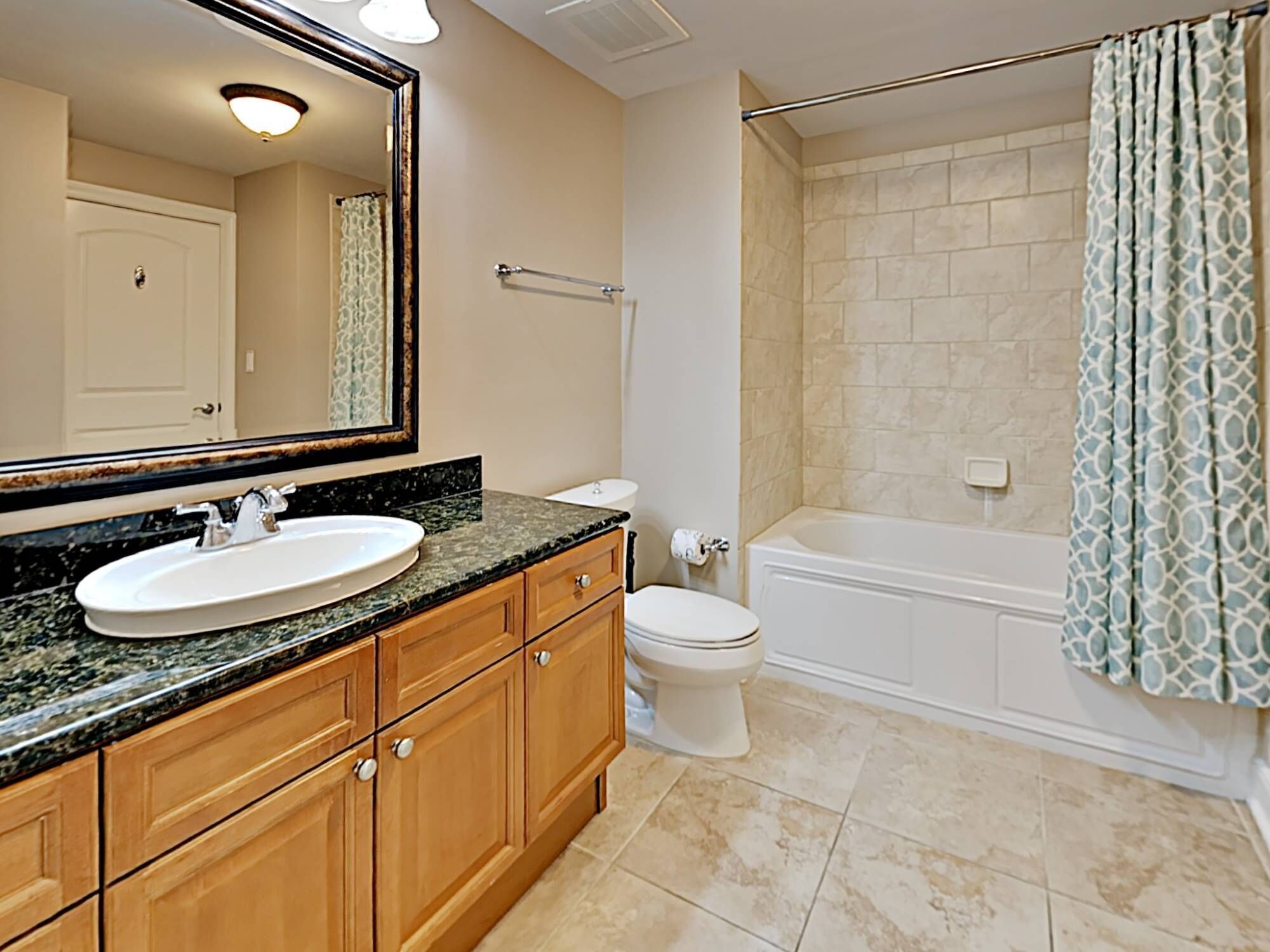 A bathroom with a sink, mirror, vanity, toilet, and bathtub.