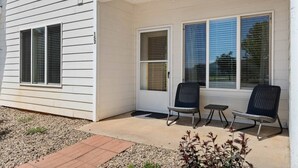 Une maison avec un porche couvert, deux chaises et une petite table.