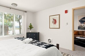 Relax in a serene bedroom with a large bed, a potted plant, and a minimalist design.