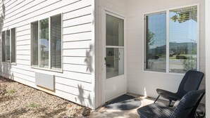 A white house with a covered porch, a door, and two windows. - The Trinity | Studio in Paradise (Paradise)