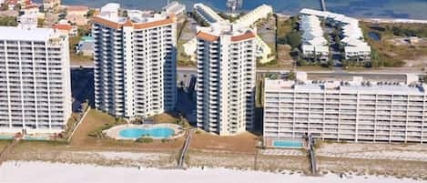 A coastal area with high-rise buildings, a beach, and a swimming pool.