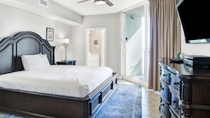 Habitación de hotel con una cama grande, ventilador de techo, televisor de pantalla plana, cómoda y vistas al exterior.