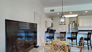 Uma sala de estar moderna com televisão de tela plana, cadeiras de vime e uma mesa de centro de vidro.
