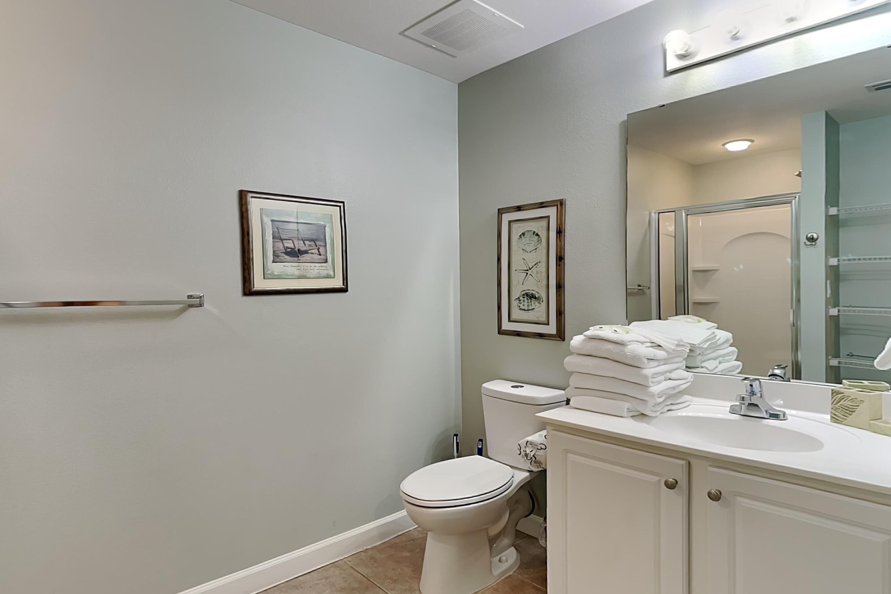A bathroom with a toilet, sink, and framed pictures on the wall.