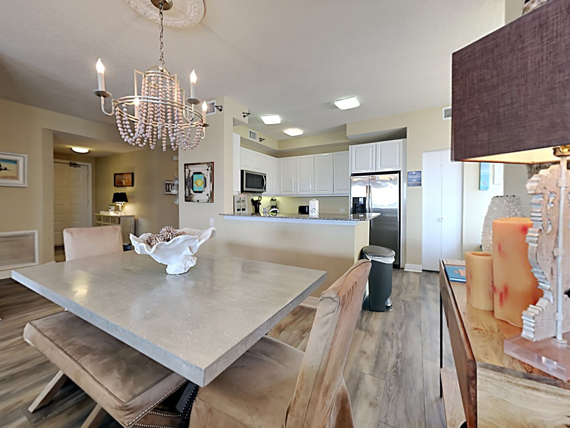 A modern kitchen with white cabinets, a central island, and a chandelier.