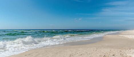 Ein Strand mit klarem Himmel und Wellen.