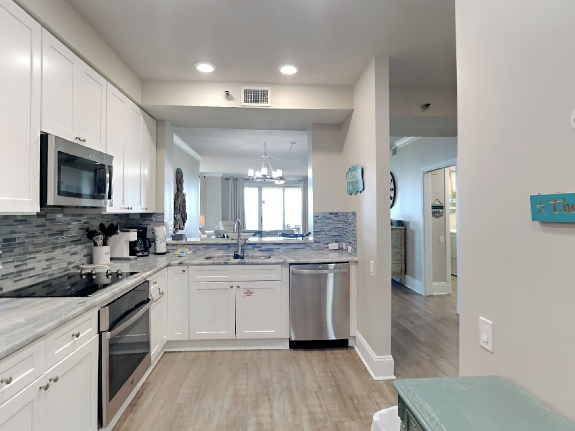 A modern kitchen with white cabinets, a stainless steel dishwasher, and a granite countertop.