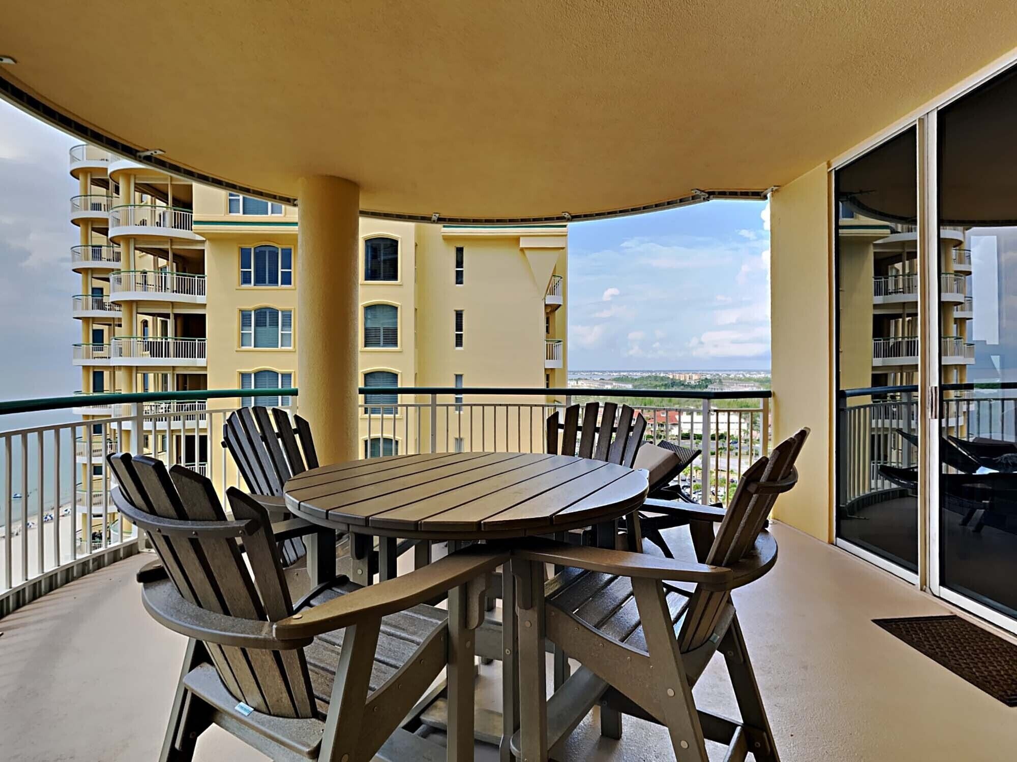 A balcony with a table and chairs, overlooking a cityscape.