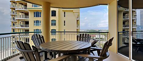 A balcony with a table and chairs, overlooking a cityscape.