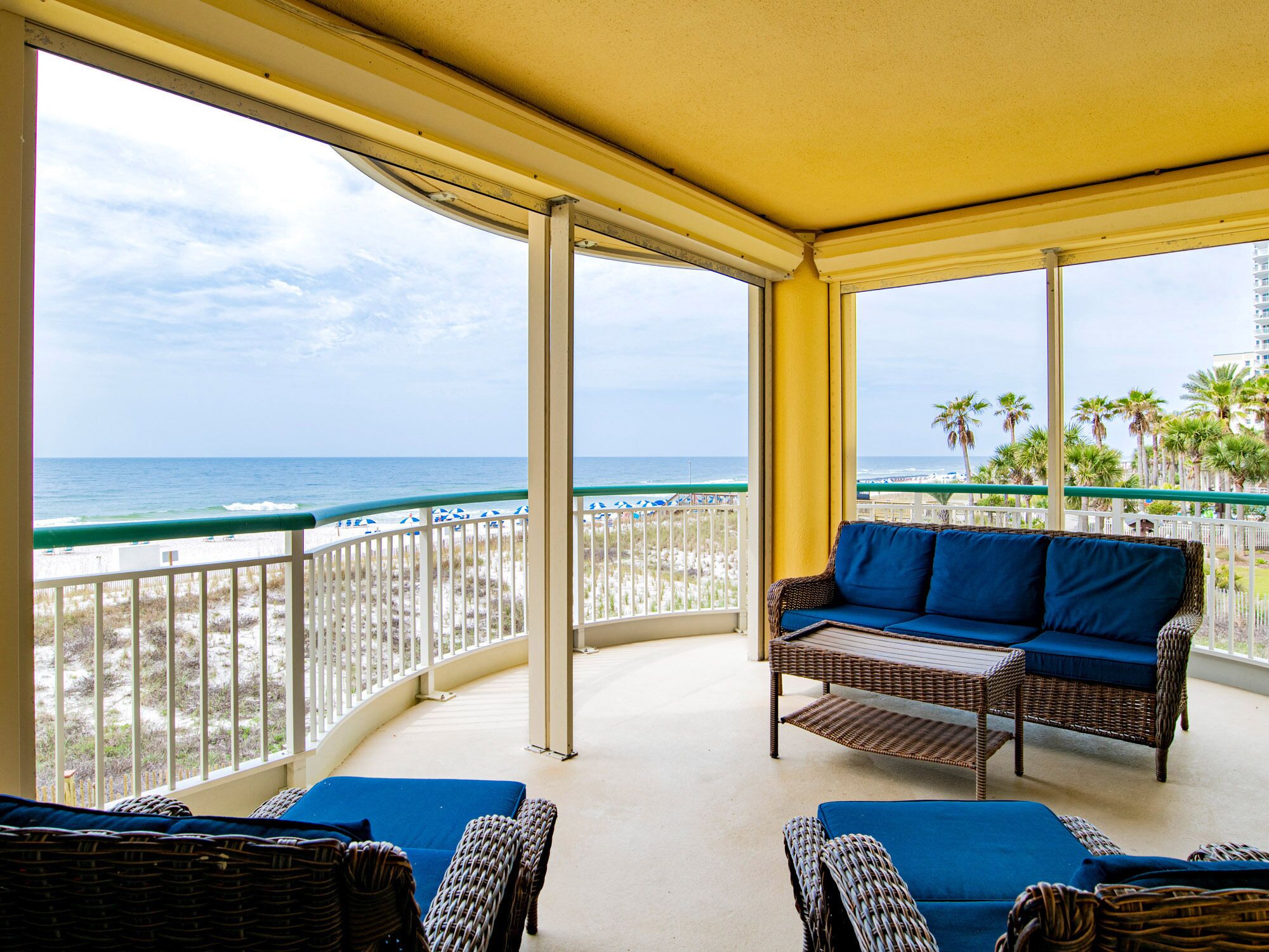 A covered balcony with wicker furniture and a view of the beach and ocean. - Beach Colony East by Southern Vacation Rentals (Pensacola)