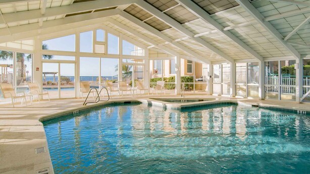 A large indoor swimming pool with clear views of the beach and palm trees. - Beach Colony East by Southern Vacation Rentals (Pensacola)