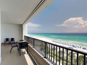 Varanda com vista para a praia, uma mesa e duas cadeiras.