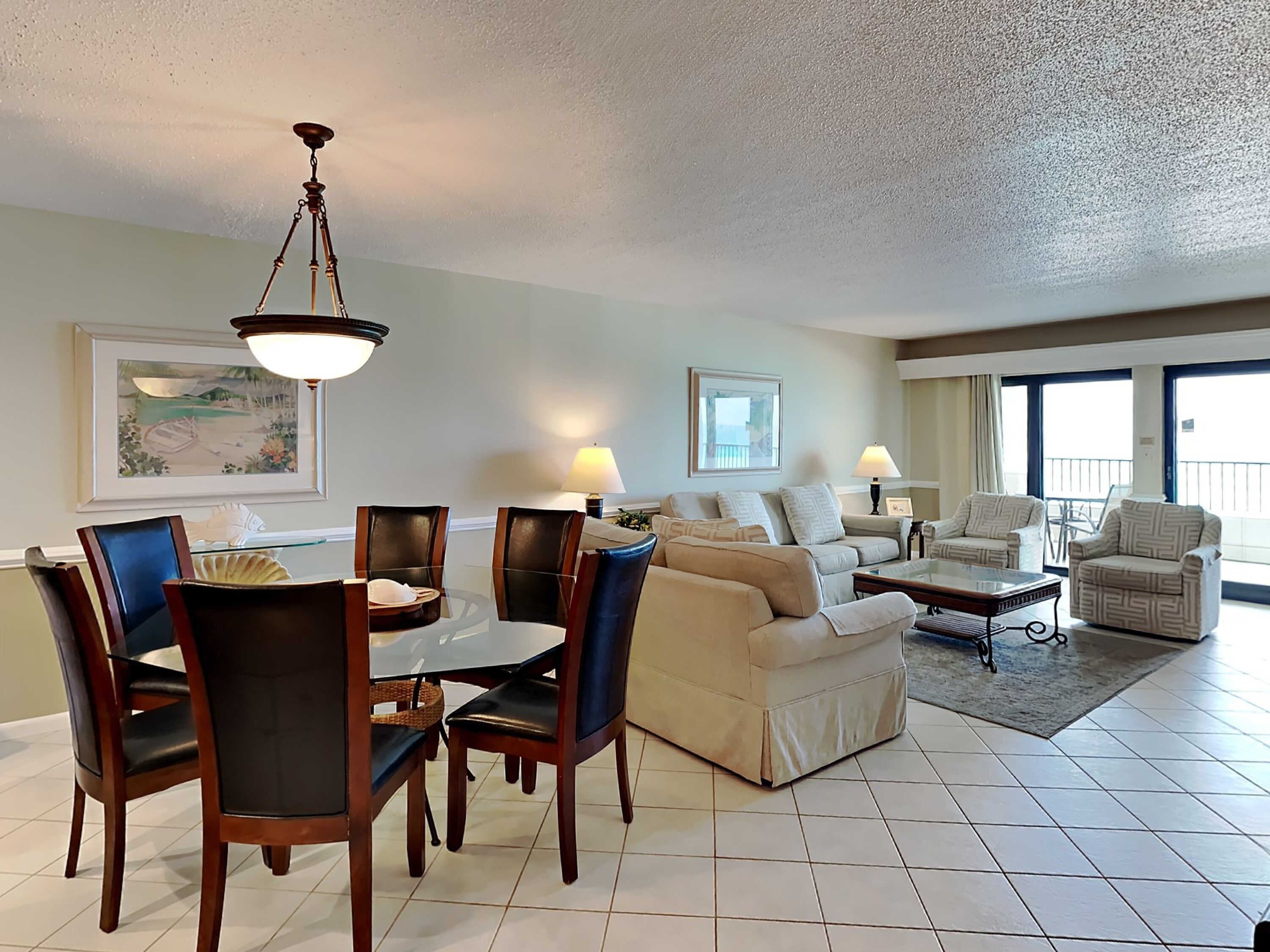 A spacious living room with a dining area, a sofa set, and a balcony with a view.
