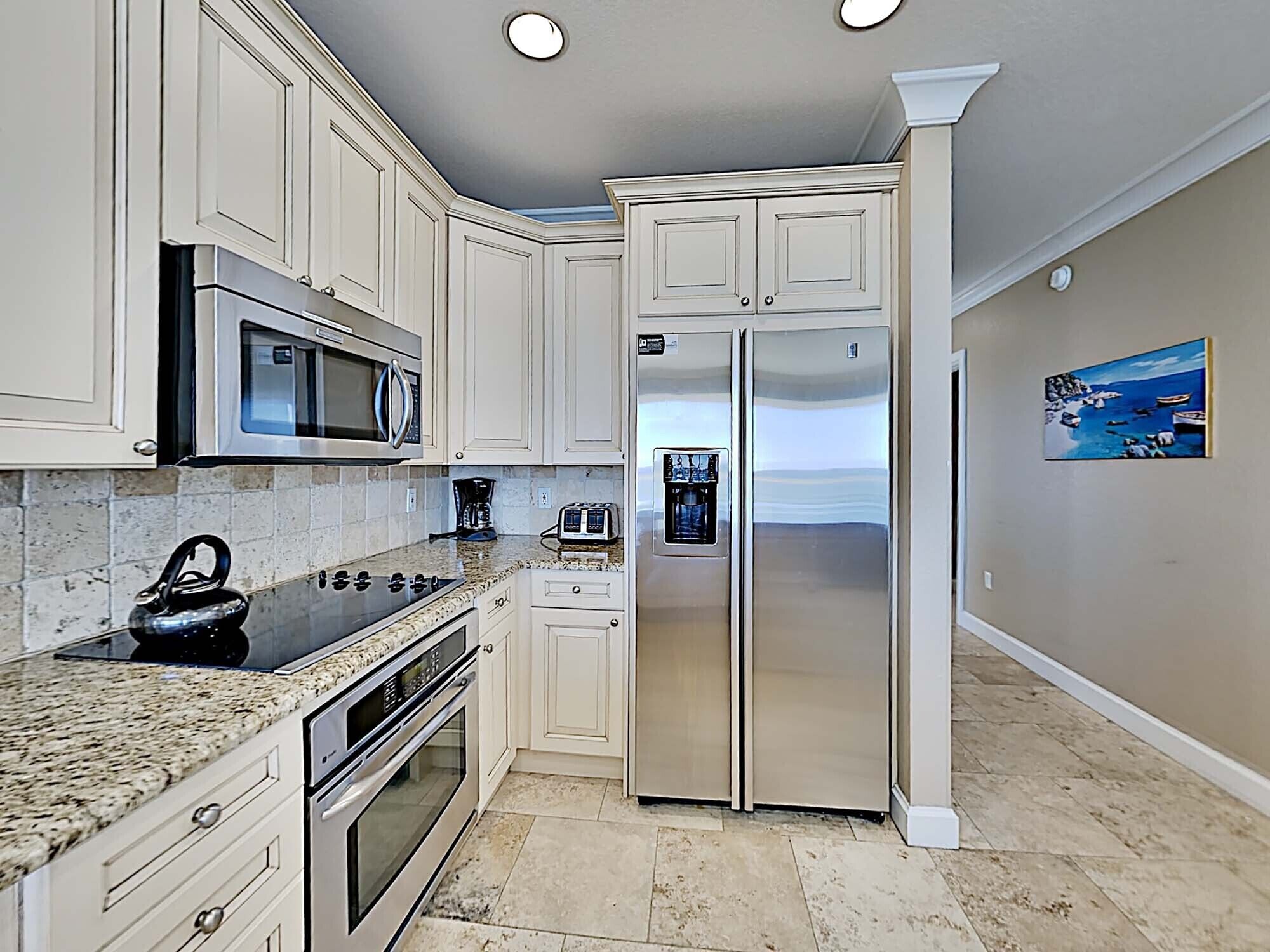 A kitchen with white cabinets, stainless steel appliances, granite countertops, and a water dispenser.
