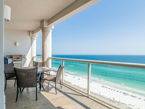A balcony with a view of the ocean and beach, featuring wicker furniture and a grill. - Beach Club by Southern Vacation Rentals (Pensacola Beach)