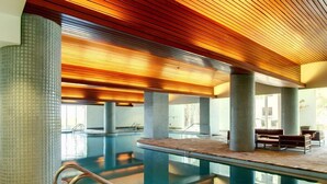 A modern indoor swimming pool with a wooden ceiling, tiled walls, and a bench area. - Beach Club by Southern Vacation Rentals (Pensacola Beach)