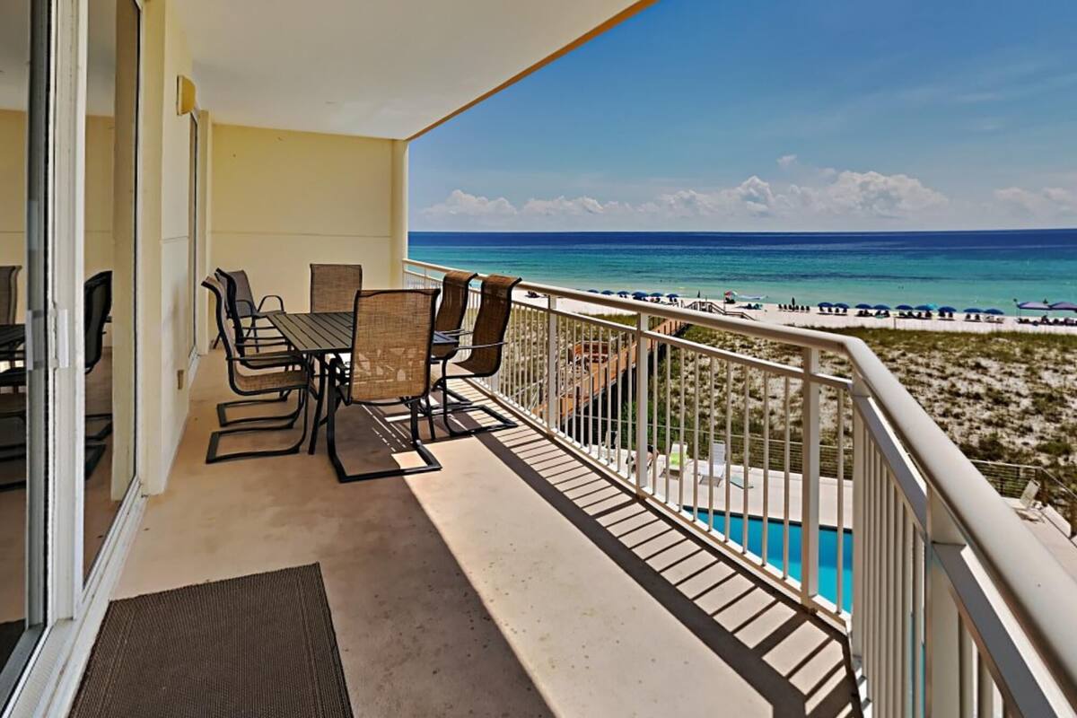 Ein Balkon mit Tisch und Stühlen mit Blick auf Strand und Pool.