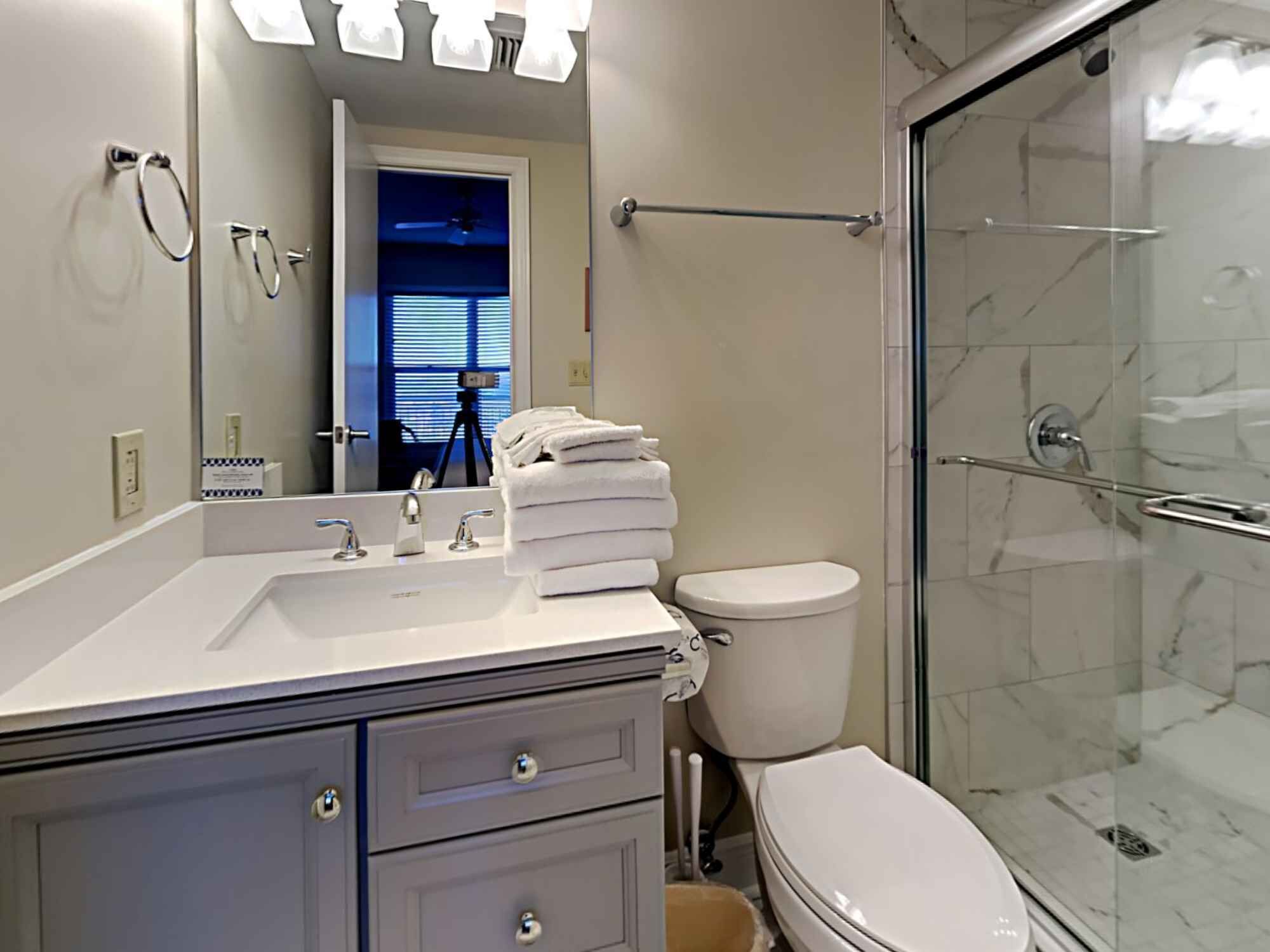 A modern bathroom with a glass shower enclosure, a white sink, and a toilet.