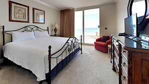 Habitación de hotel con cama, televisor, cómoda y vista al océano.