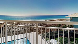 Un balcón con piscina, con vista a una playa y al océano.