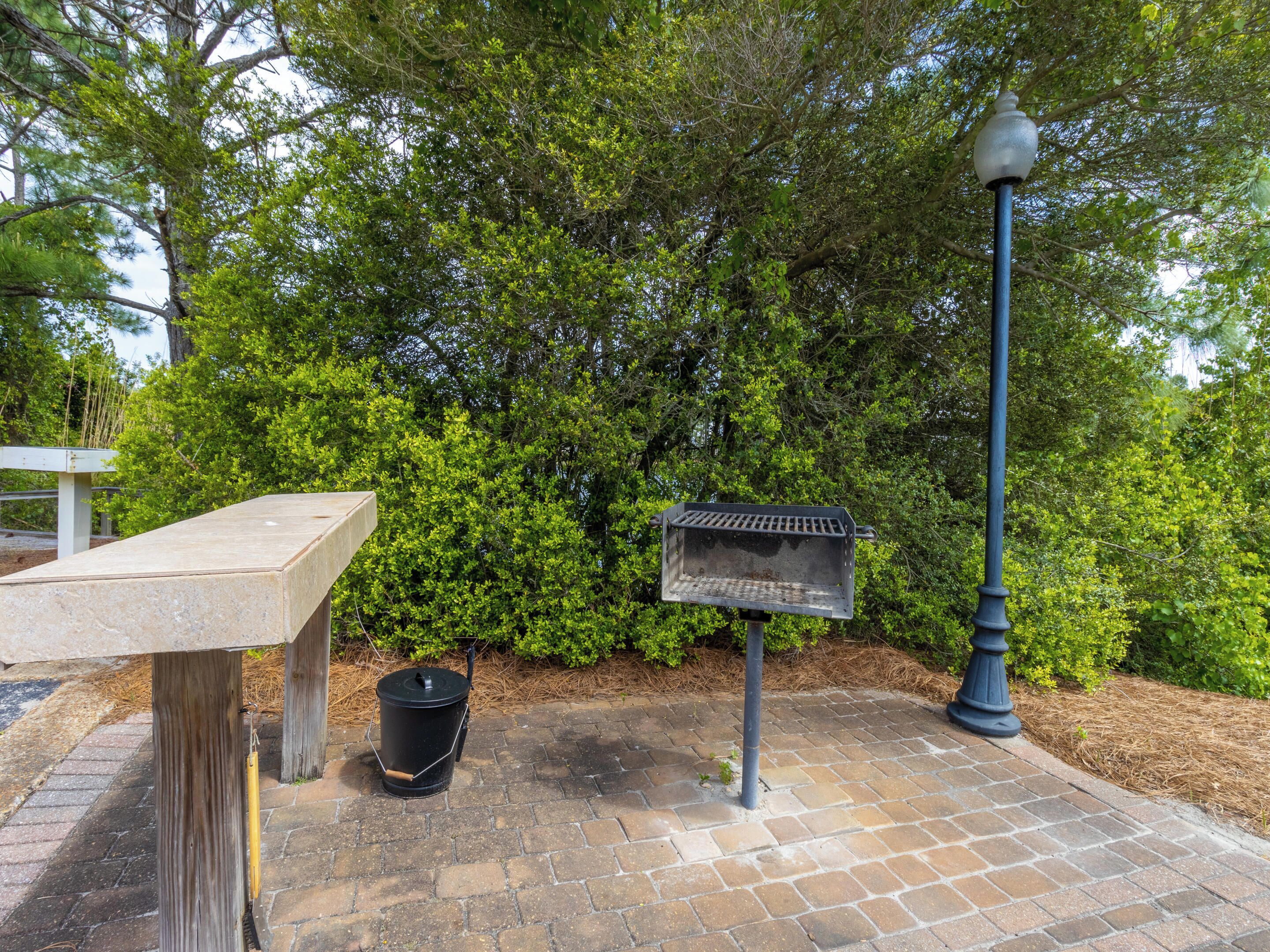 A picnic table, a trash bin, and a sign post in a park.