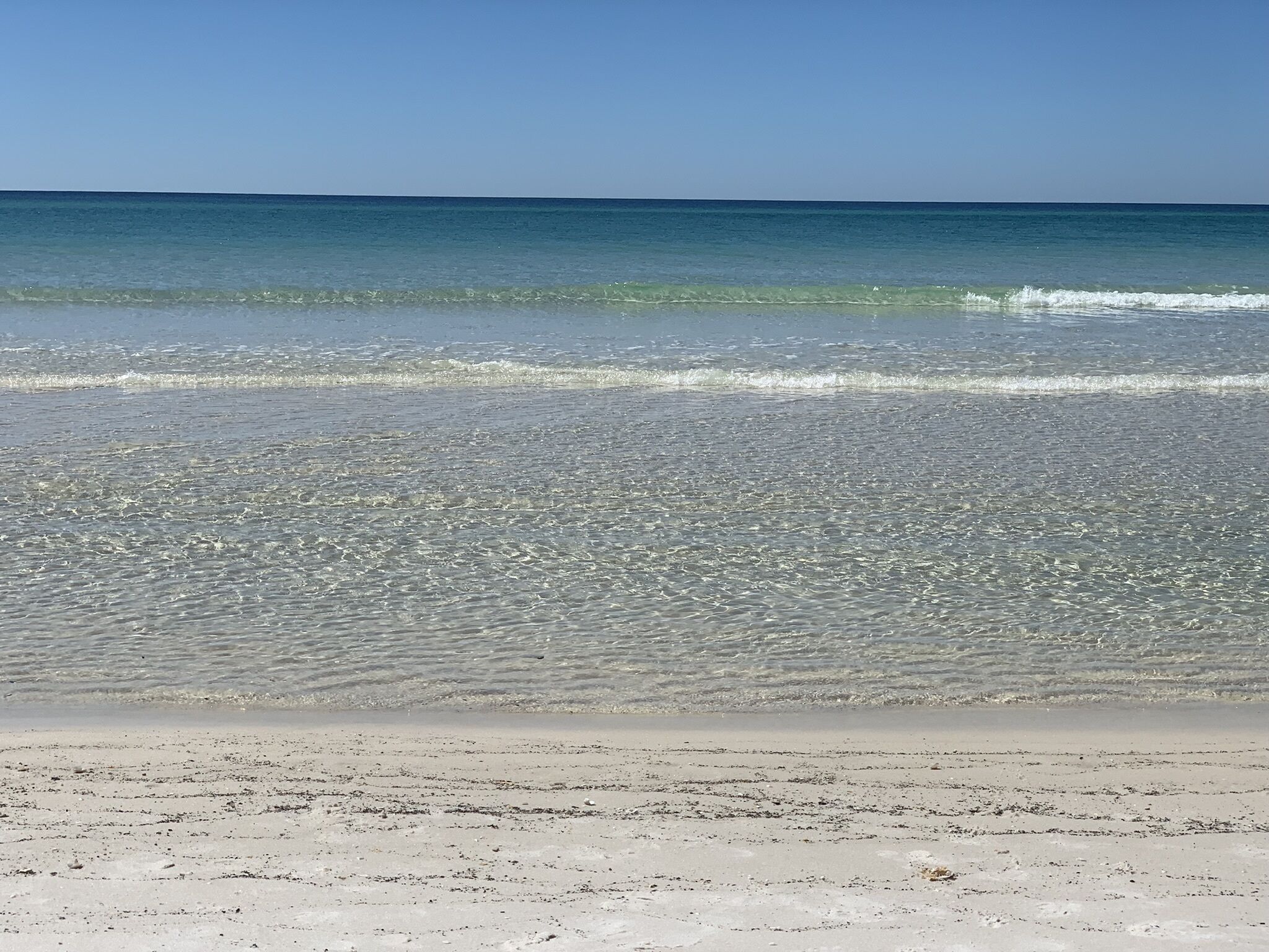 A beach with clear water and a sandy shore.