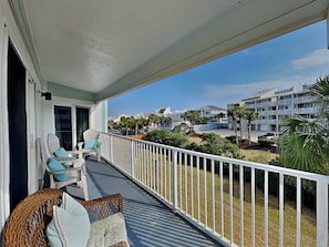 Een balkon met rieten meubels en uitzicht op een woonwijk.