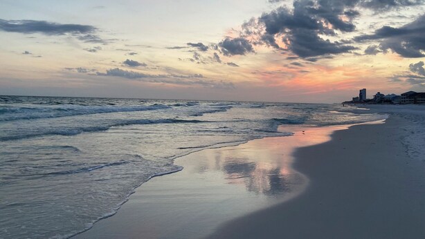 Une plage avec des vagues et un coucher de soleil.